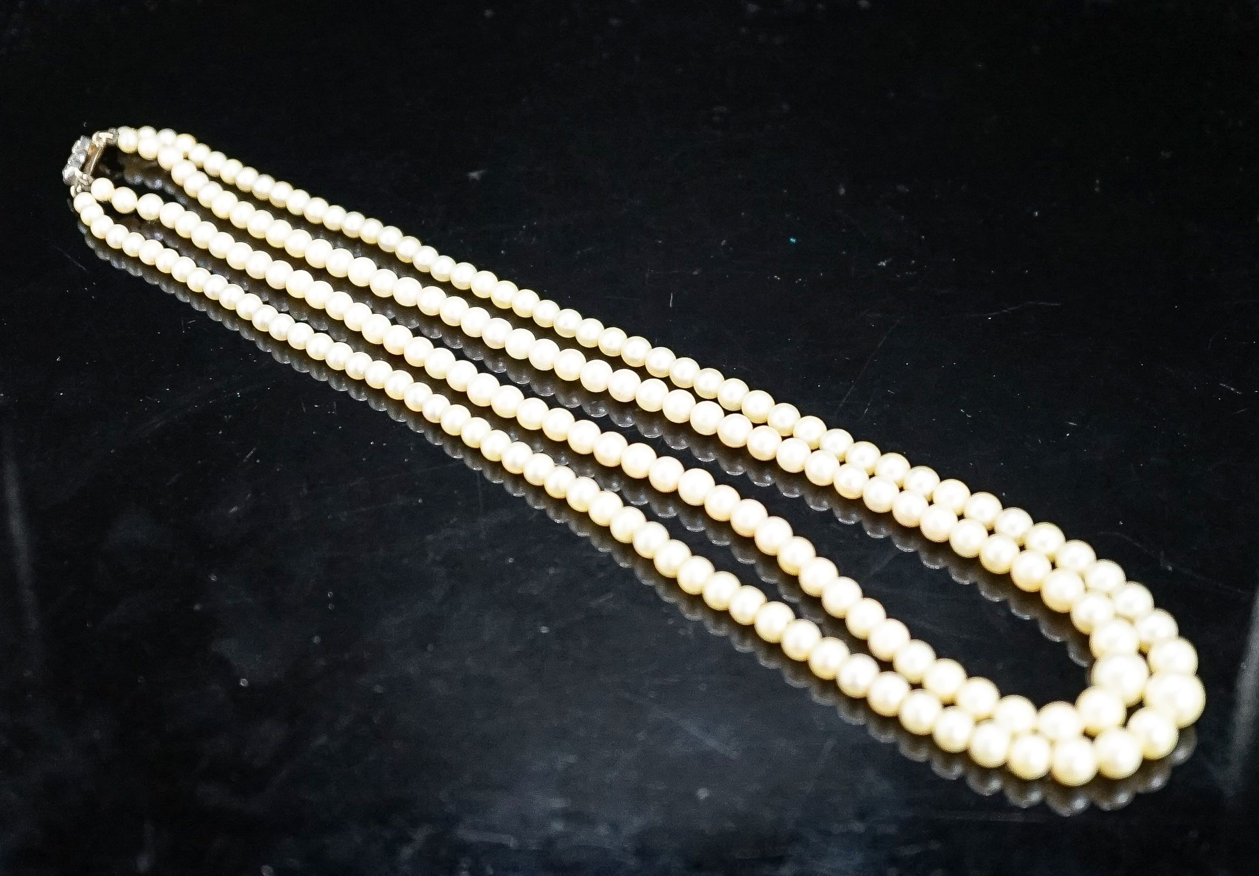 A double strand graduated cultured pearl choker necklace, with three stone diamond set clasp, 39cm.